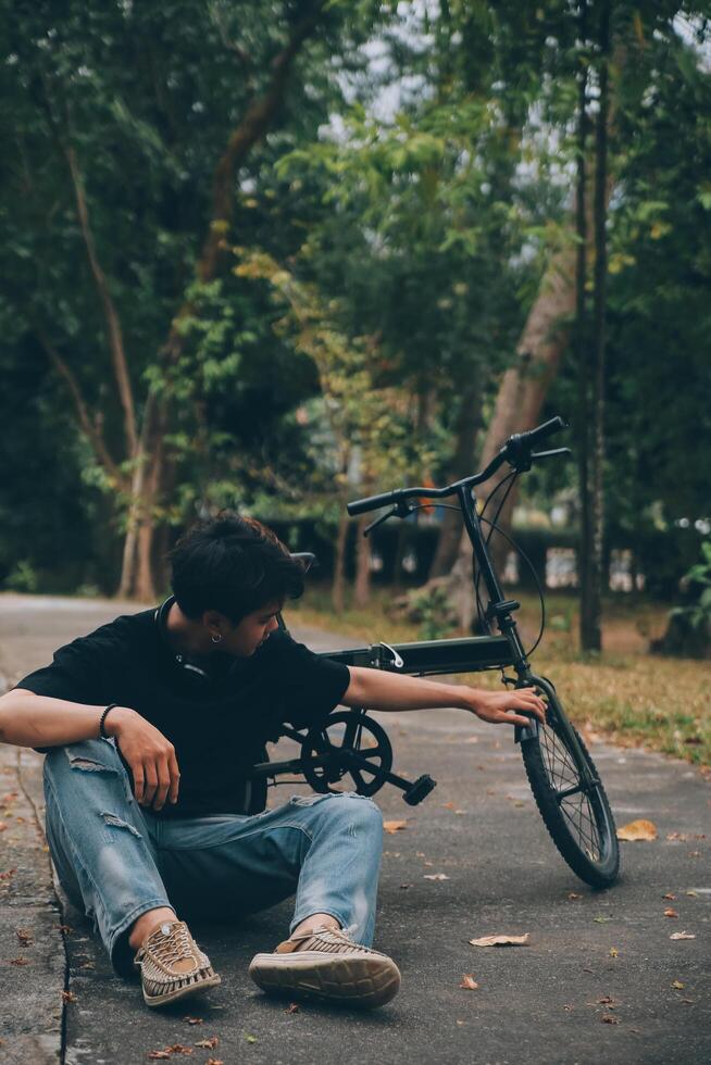 Young handsome bearded man taking a break while travelling the city with his bicycle using his digital tablet looking away thoughtfully photo