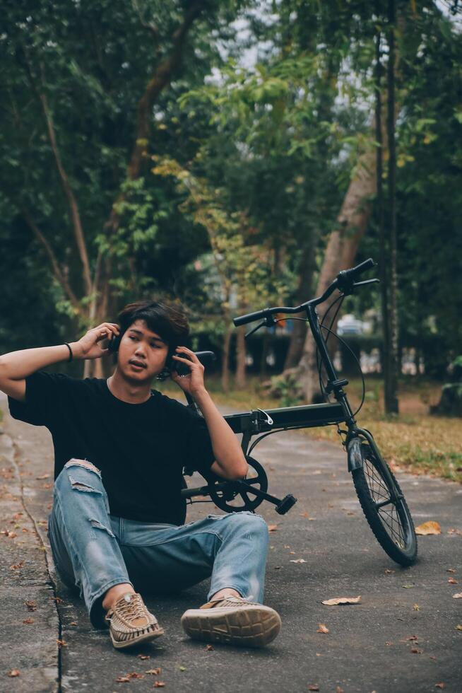 Young handsome bearded man taking a break while travelling the city with his bicycle using his digital tablet looking away thoughtfully photo