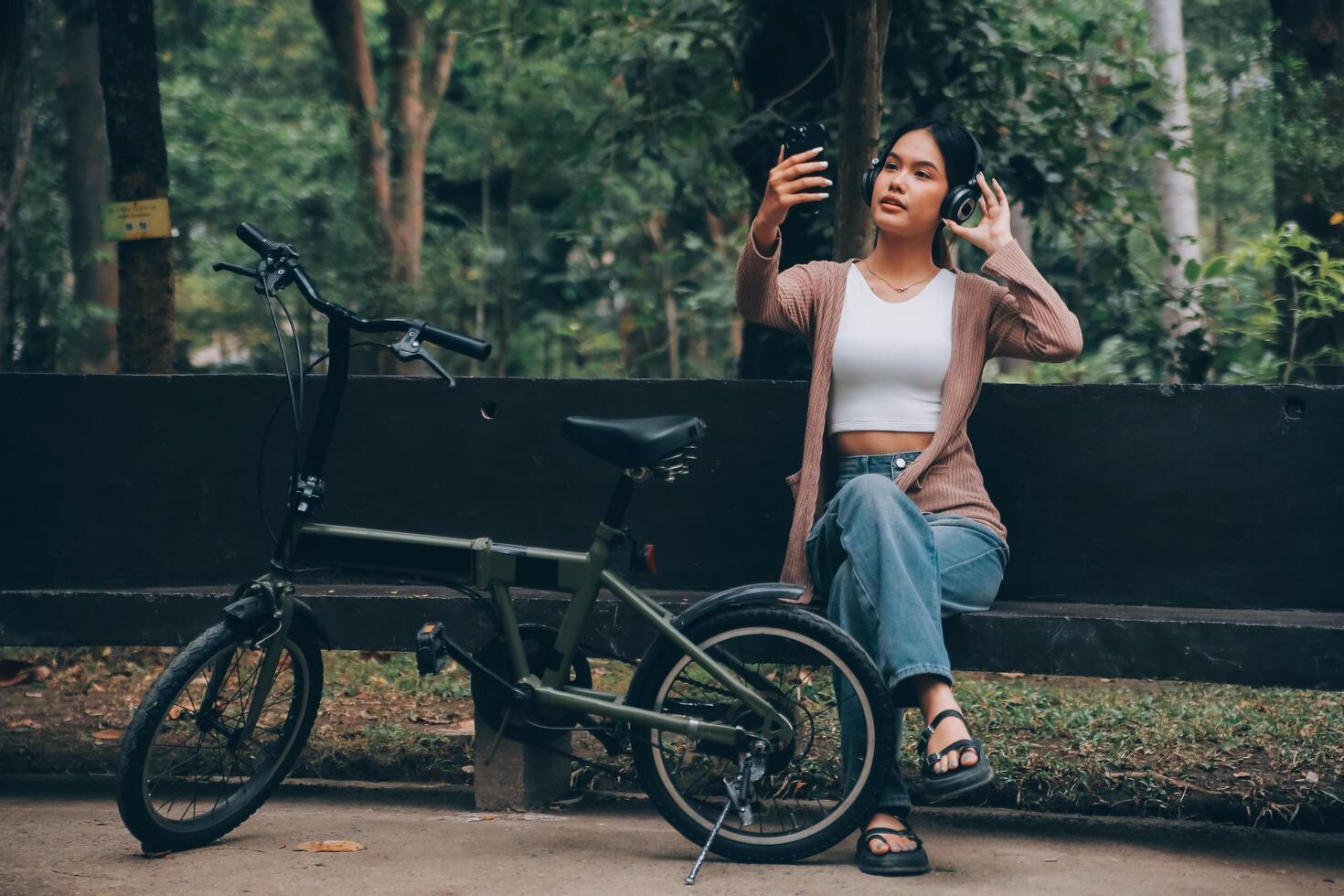 contento joven asiático mujer mientras montando un bicicleta en un ciudad parque. ella sonrió utilizando el bicicleta de transporte. ambientalmente simpático concepto. foto