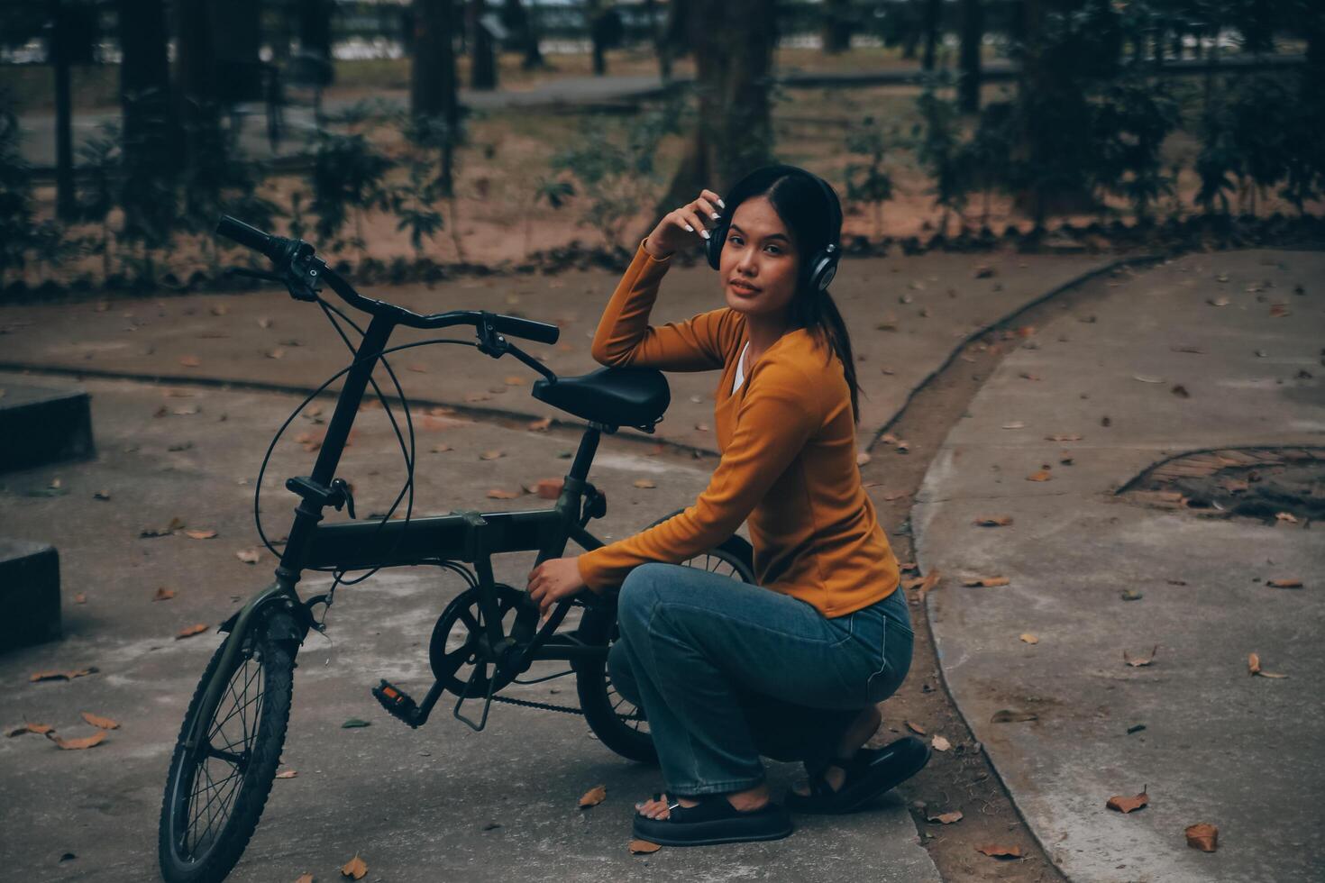 Happy young Asian woman while riding a bicycle in a city park. She smiled using the bicycle of transportation. Environmentally friendly concept. photo