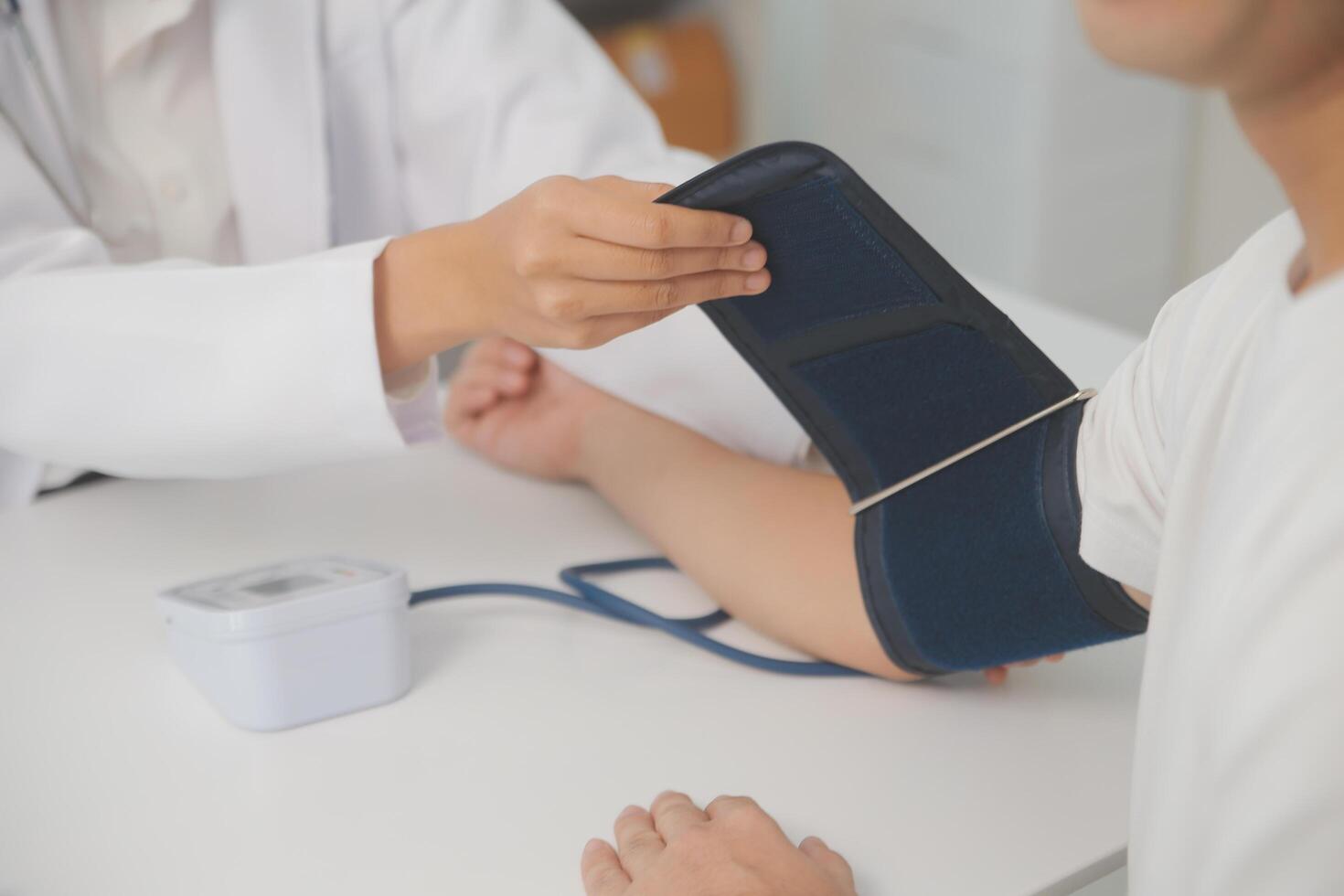 Male doctor uses a blood pressure monitor to check the body pressure and pulse of the patients who come to the hospital for check-ups, Medical treatment and health care concept. photo