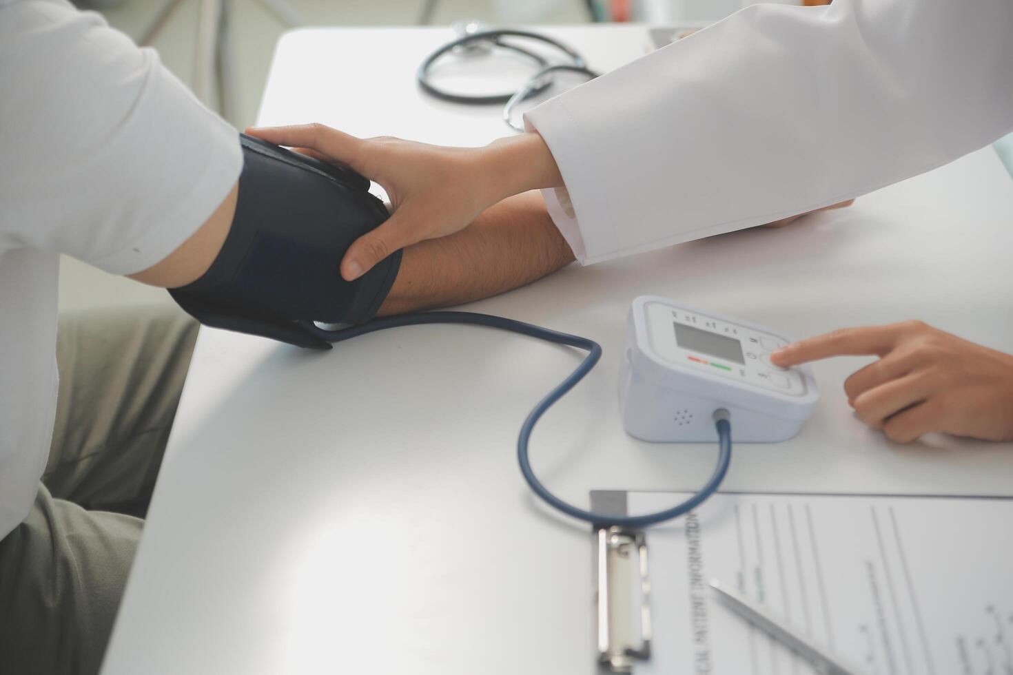 Male doctor uses a blood pressure monitor to check the body pressure and pulse of the patients who come to the hospital for check-ups, Medical treatment and health care concept. photo