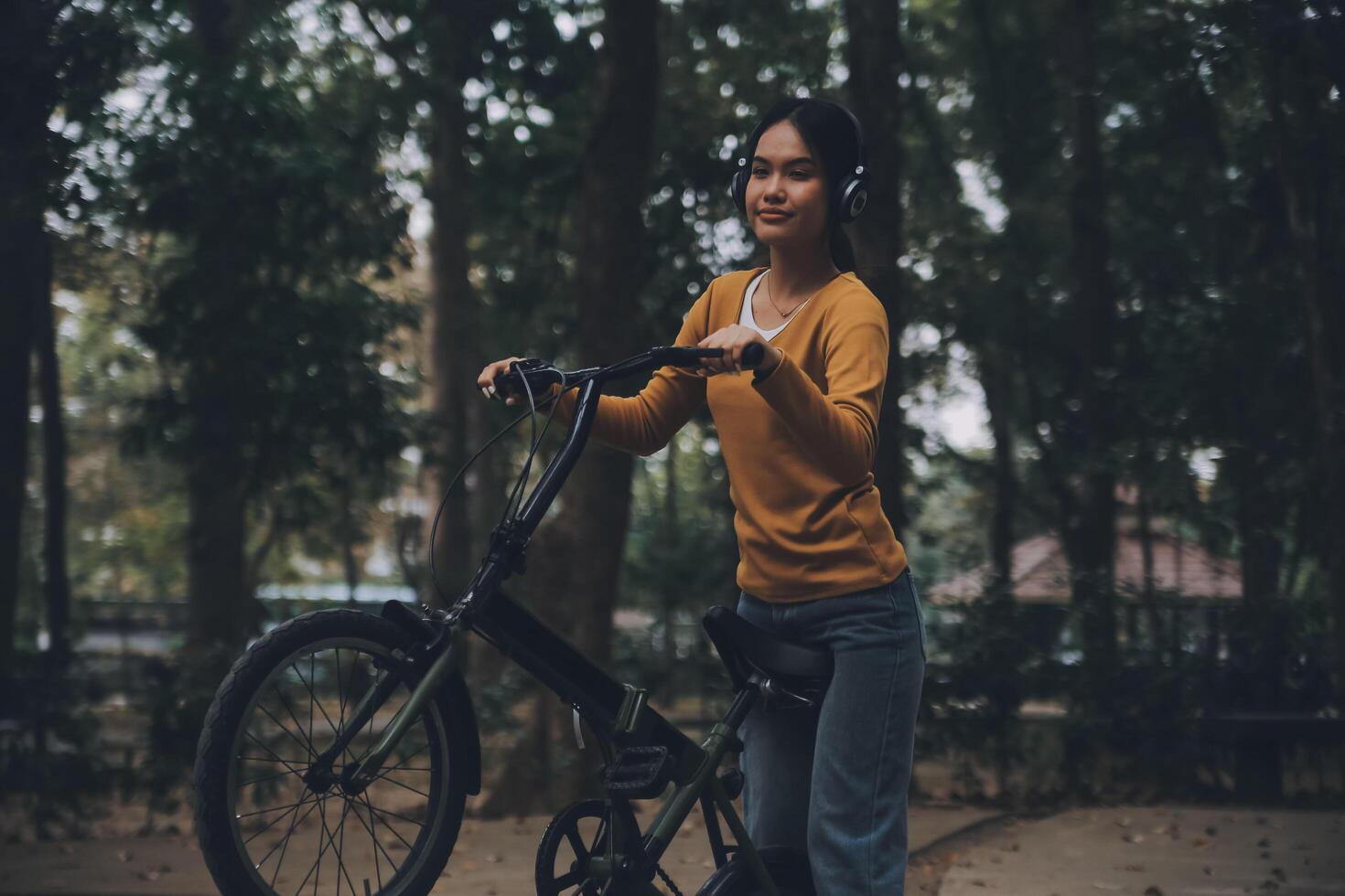 Happy young Asian woman while riding a bicycle in a city park. She smiled using the bicycle of transportation. Environmentally friendly concept. photo