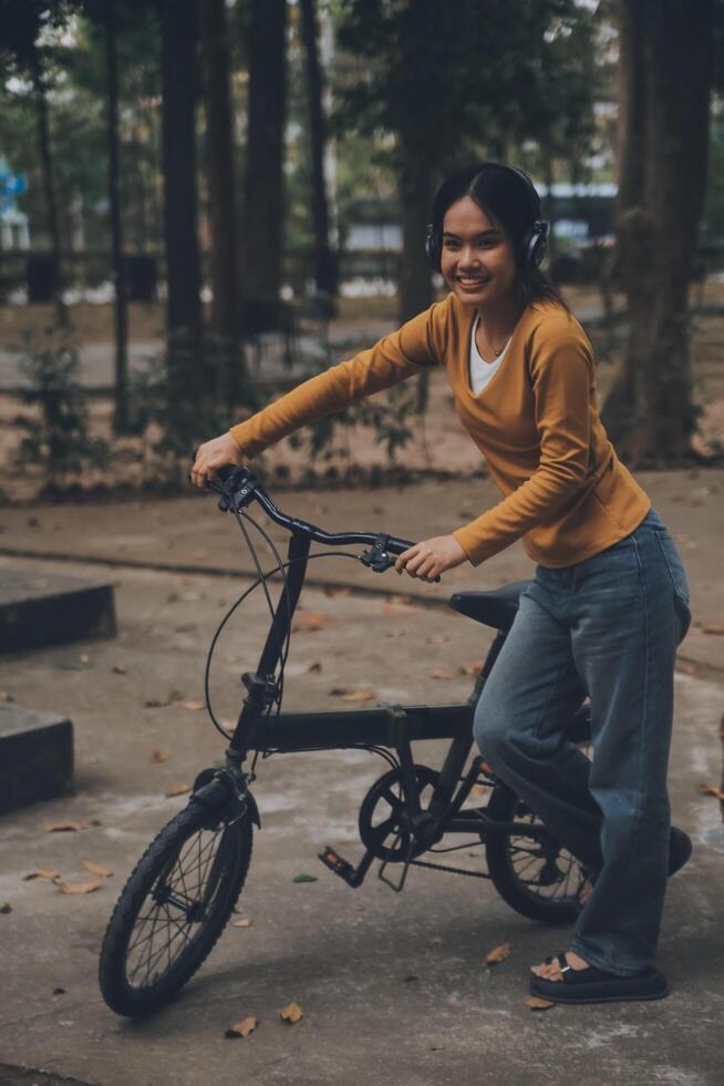 Happy young Asian woman while riding a bicycle in a city park. She smiled using the bicycle of transportation. Environmentally friendly concept. photo