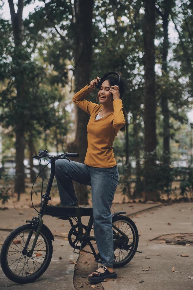 Happy young Asian woman while riding a bicycle in a city park. She smiled using the bicycle of transportation. Environmentally friendly concept. photo