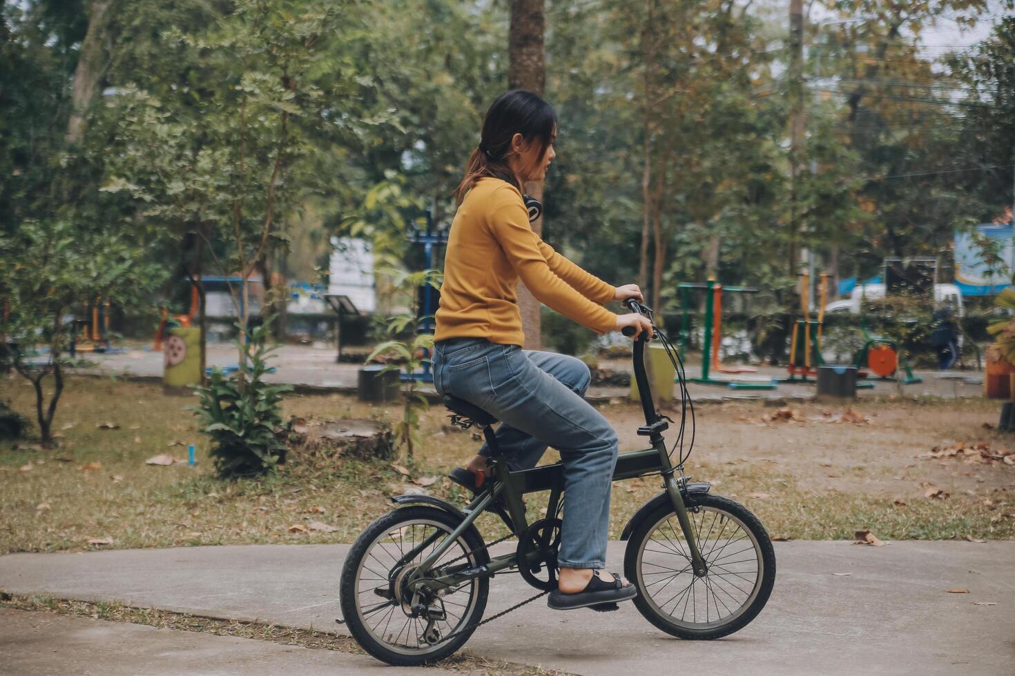 Happy young Asian woman while riding a bicycle in a city park. She smiled using the bicycle of transportation. Environmentally friendly concept. photo