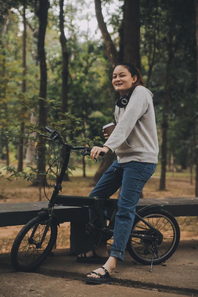 Happy Asian young woman walk and ride bicycle in park, street city her smiling using bike of transportation, ECO friendly, People lifestyle concept. photo