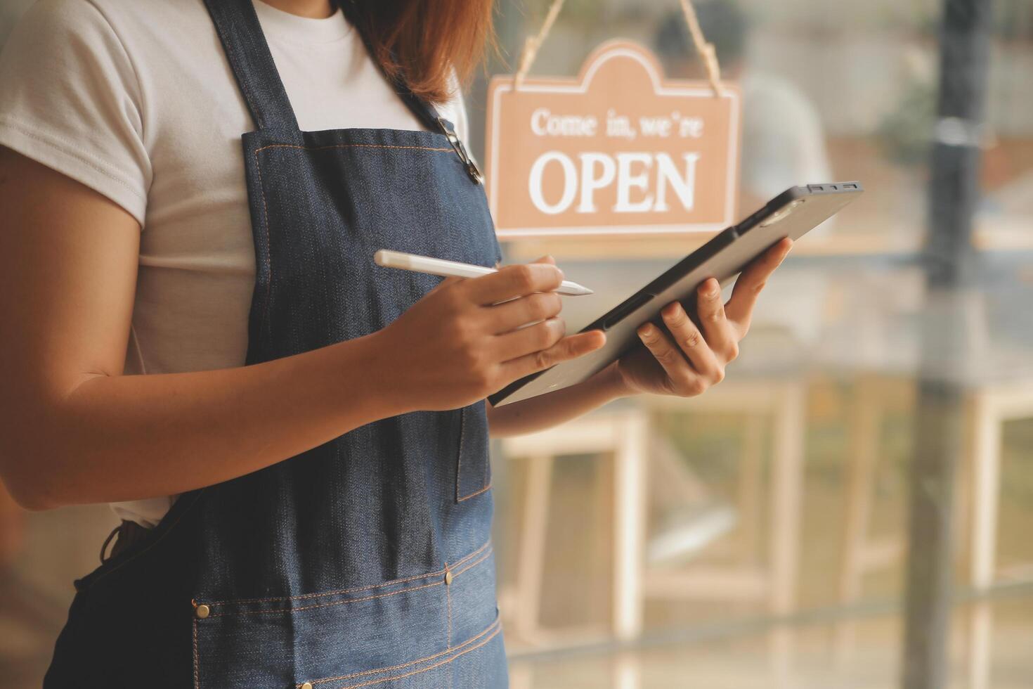 Startup successful small business owner sme beauty girl stand with tablet smartphone in coffee shop restaurant. Portrait of asian tan woman barista cafe owner. SME entrepreneur seller business concept photo