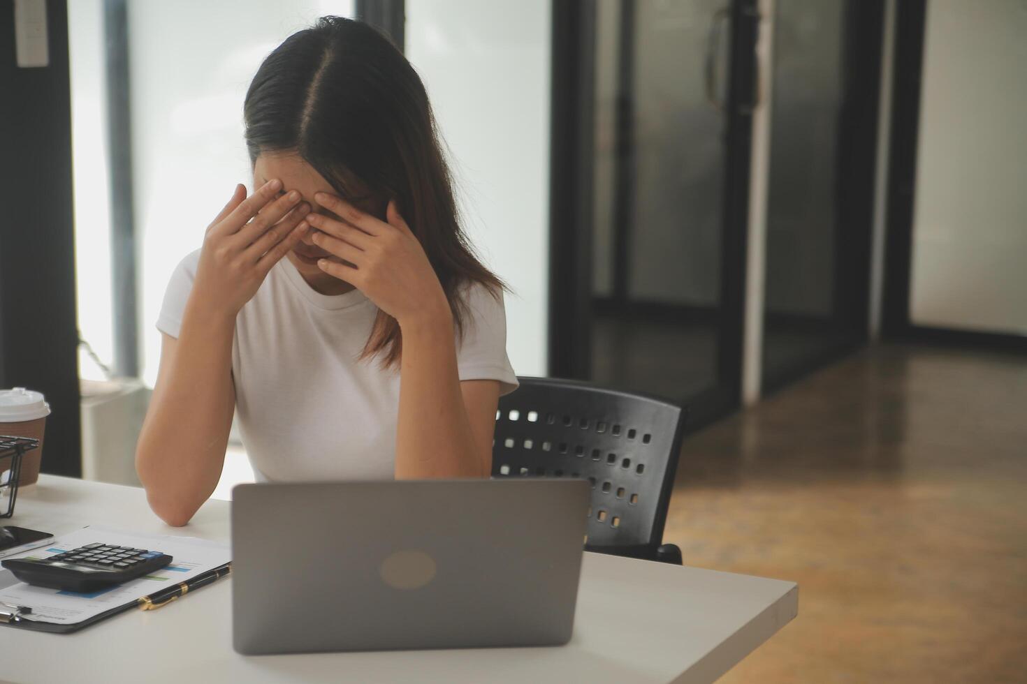 cansado negocio mujer soñoliento y aburrido desde sentado a un escritorio para un largo hora y tiene oficina síndrome foto