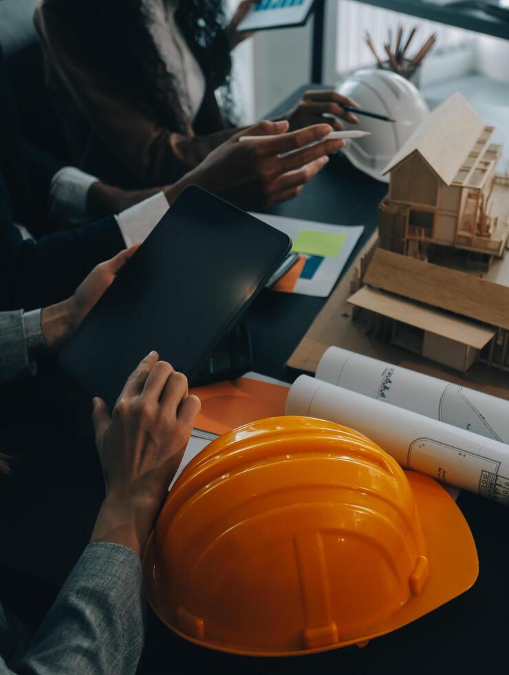 reunión de trabajo en equipo de ingenieros, trabajo de dibujo en la reunión de planos para el trabajo del proyecto con un socio en la construcción de modelos y herramientas de ingeniería en el concepto de sitio de trabajo, construcción y estructura. foto