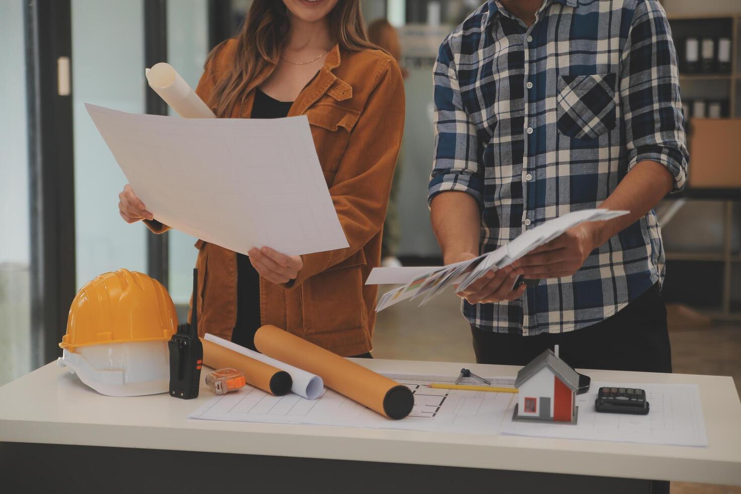 masculino y hembra industrial ingenieros en difícil sombreros discutir nuevo proyecto mientras utilizando ordenador portátil. ellos hacer demostración gestos ellos trabajo en un pesado industria fabricación fábrica. foto