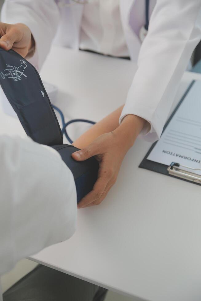 Male doctor uses a blood pressure monitor to check the body pressure and pulse of the patients who come to the hospital for check-ups, Medical treatment and health care concept. photo