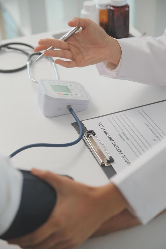 Male doctor uses a blood pressure monitor to check the body pressure and pulse of the patients who come to the hospital for check-ups, Medical treatment and health care concept. photo