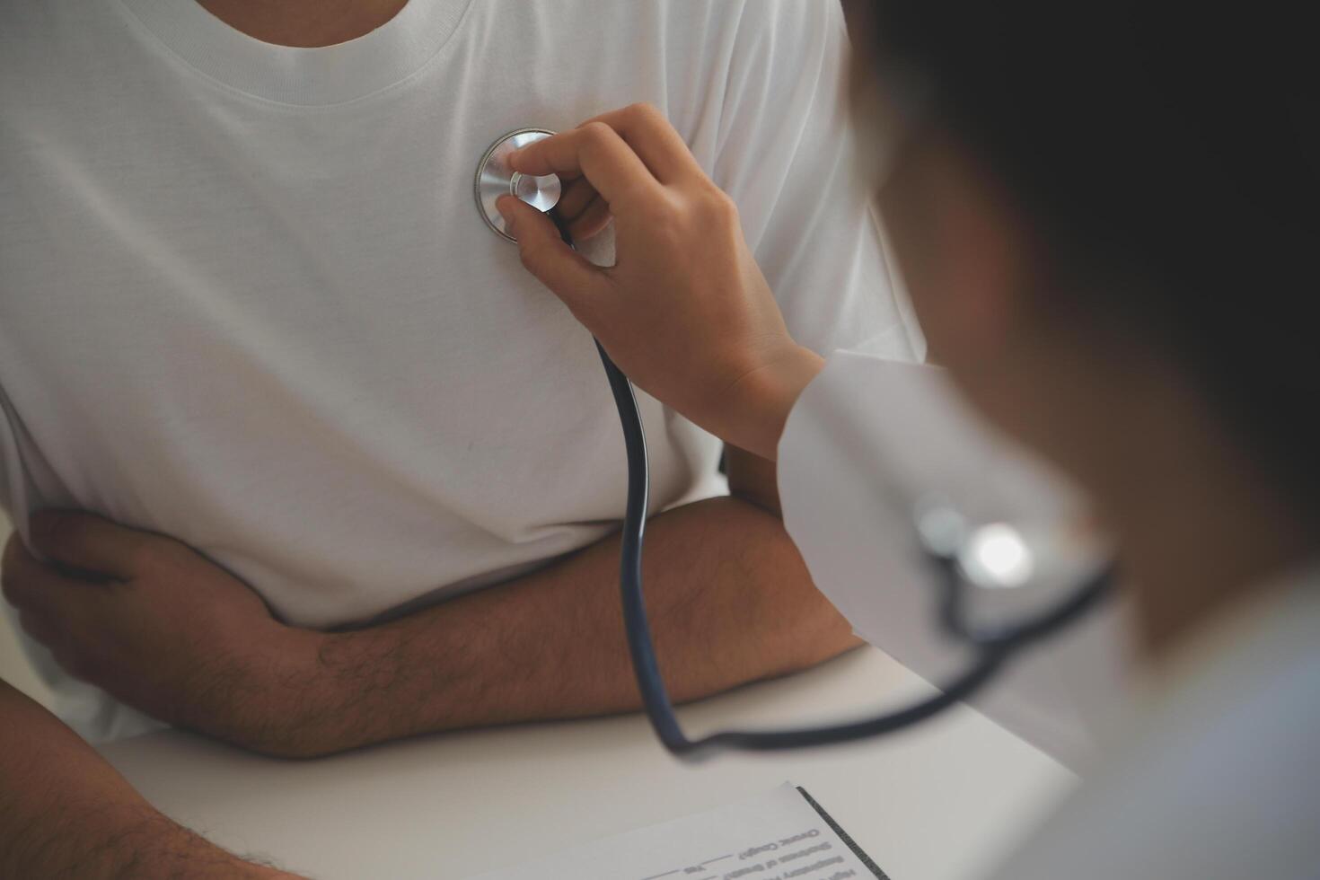 Young doctor is using a stethoscope listen to the heartbeat of the patient. Shot of a female doctor giving a male patient a check up photo