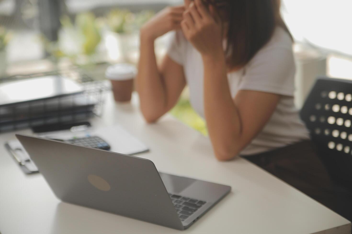 cansado negocio mujer soñoliento y aburrido desde sentado a un escritorio para un largo hora y tiene oficina síndrome foto