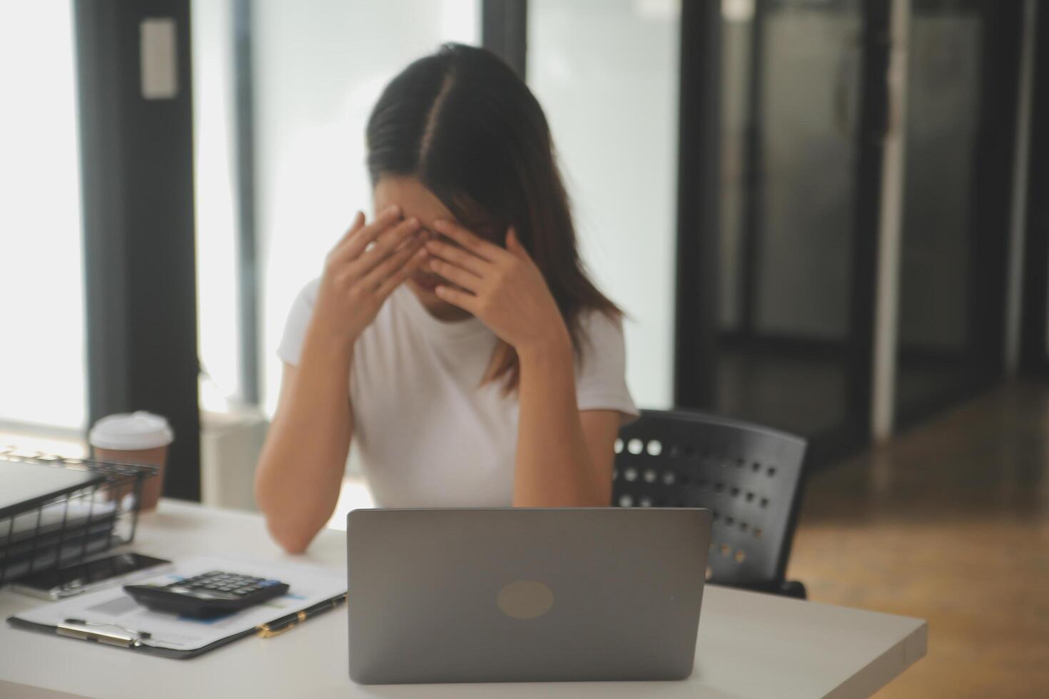 cansado negocio mujer soñoliento y aburrido desde sentado a un escritorio para un largo hora y tiene oficina síndrome foto