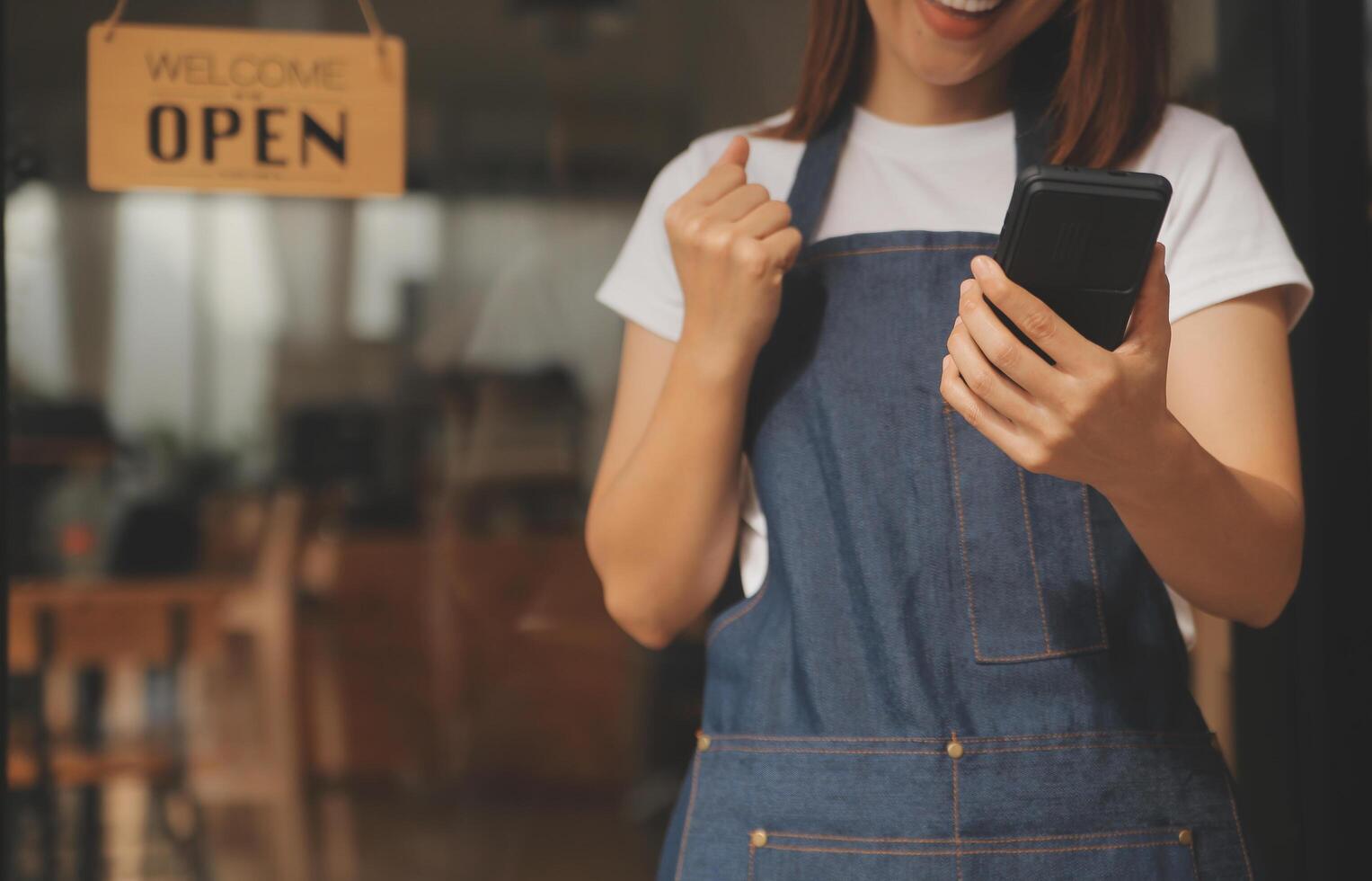 Startup successful small business owner sme beauty girl stand with tablet smartphone in coffee shop restaurant. Portrait of asian tan woman barista cafe owner. SME entrepreneur seller business concept photo