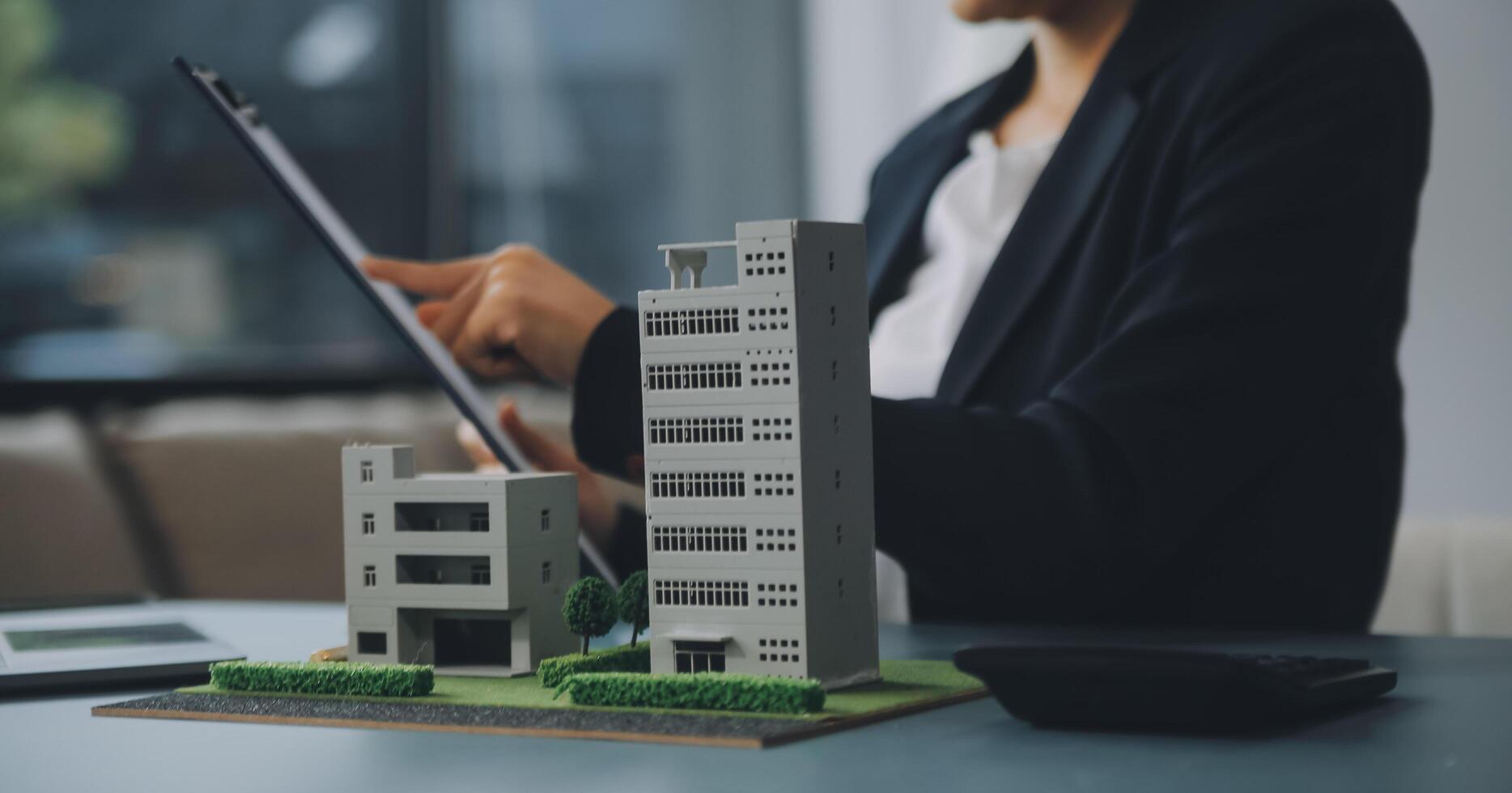 Close up realtor sit at table holds tiny house model, layout of cottage. Real estate purchase, new property, ownership, construction company make special offer to client, affordable dwelling concept photo