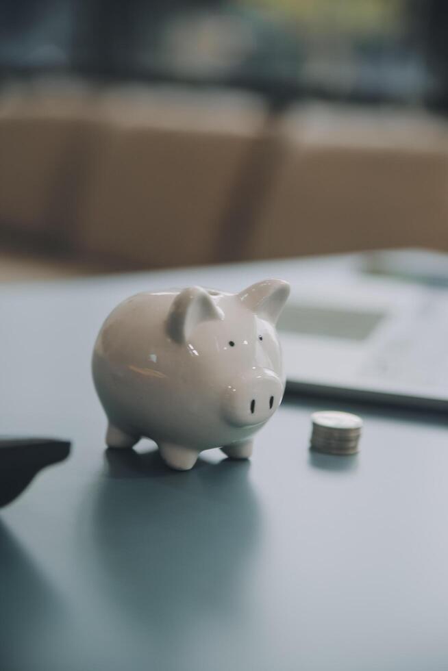 Young Asian woman saving for retirement Saving money through a piggy bank and taking notes on notebook, savings concept. photo