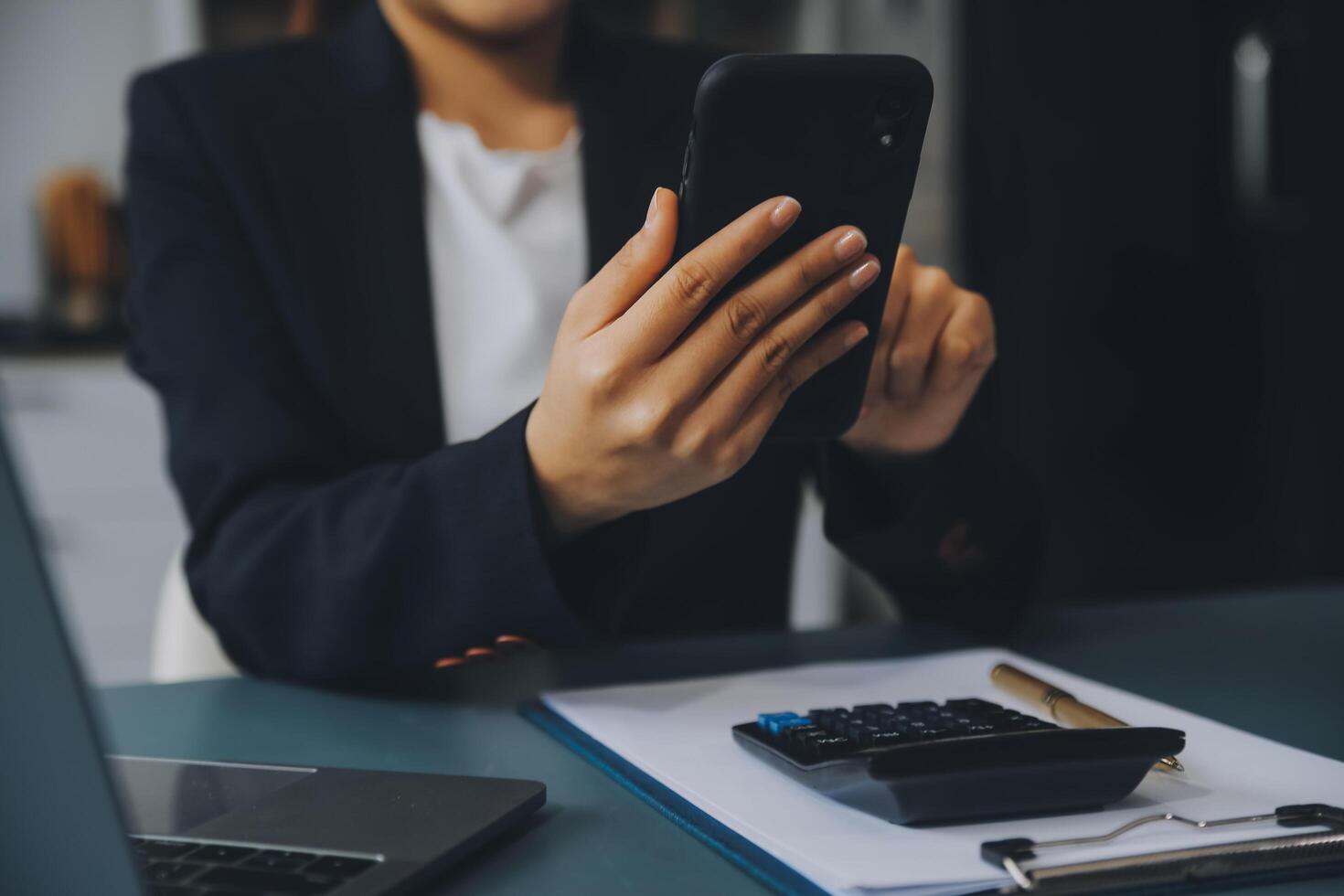 Hispanic businesswoman in formal attire in her office happy and cheerful while using smartphones and working. Young businesswoman using apps on cell phones, reading news, fast connection photo