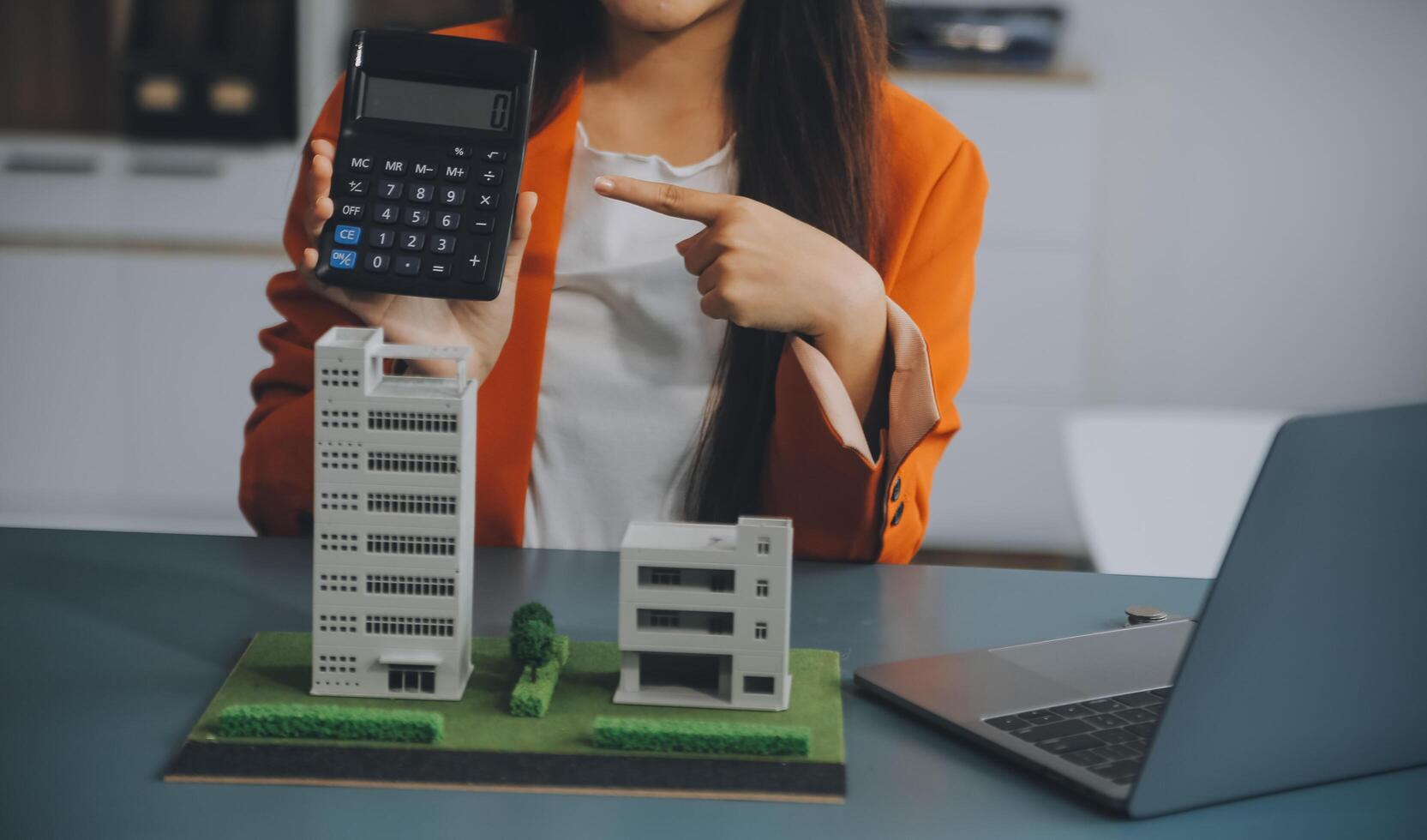 Close up realtor sit at table holds tiny house model, layout of cottage. Real estate purchase, new property, ownership, construction company make special offer to client, affordable dwelling concept photo
