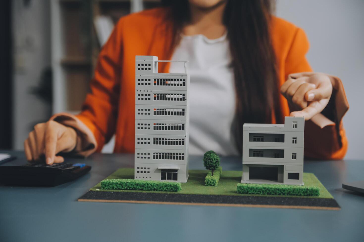 Close up realtor sit at table holds tiny house model, layout of cottage. Real estate purchase, new property, ownership, construction company make special offer to client, affordable dwelling concept photo