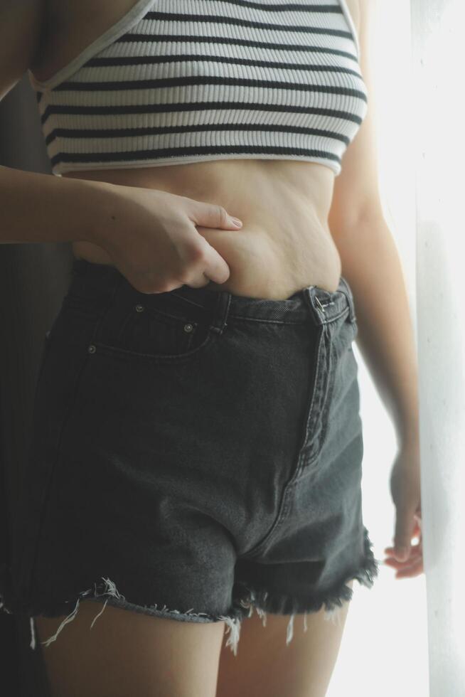Women body fat belly. Obese woman hand holding excessive belly fat. diet lifestyle concept to reduce belly and shape up healthy stomach muscle. photo