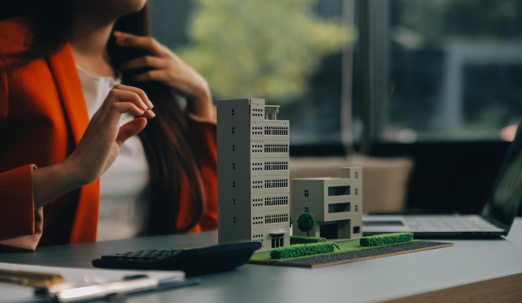 Close up realtor sit at table holds tiny house model, layout of cottage. Real estate purchase, new property, ownership, construction company make special offer to client, affordable dwelling concept photo