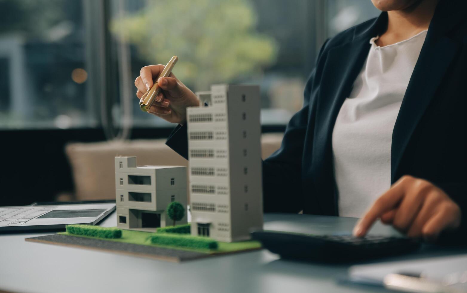 Close up realtor sit at table holds tiny house model, layout of cottage. Real estate purchase, new property, ownership, construction company make special offer to client, affordable dwelling concept photo