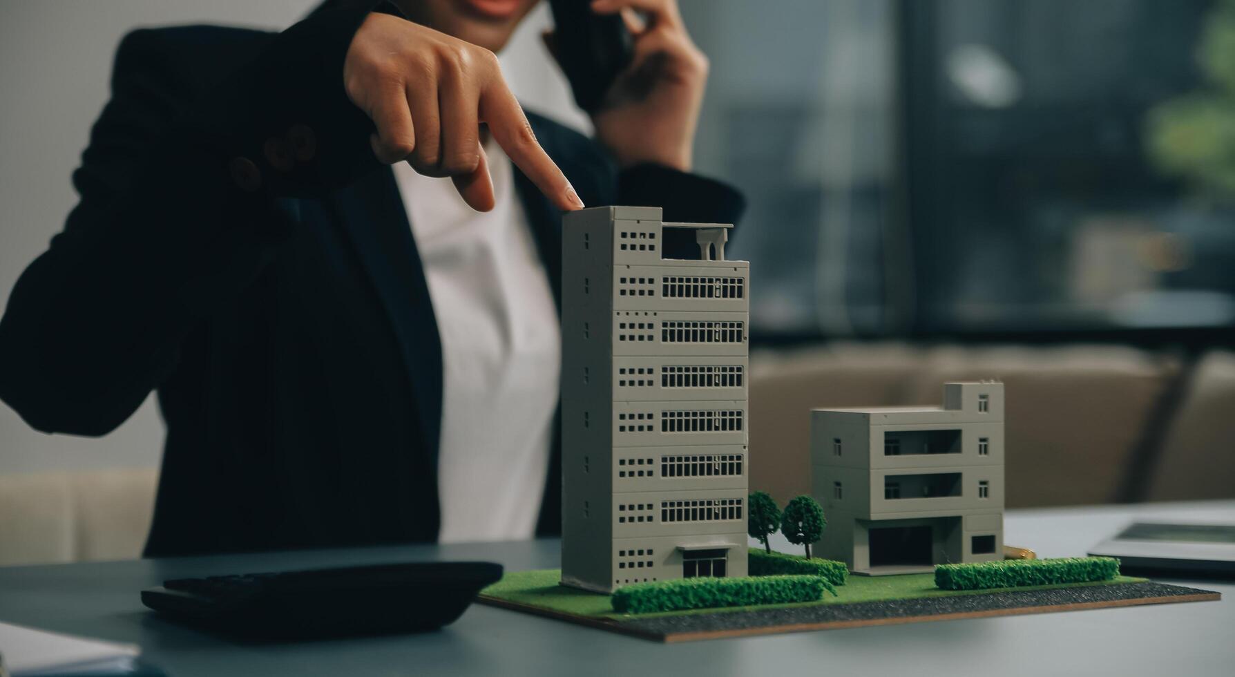 Close up realtor sit at table holds tiny house model, layout of cottage. Real estate purchase, new property, ownership, construction company make special offer to client, affordable dwelling concept photo