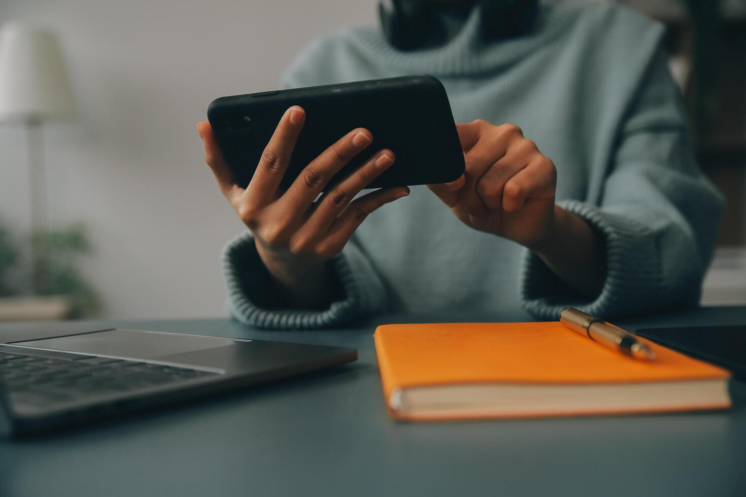 Happy pretty millennial Indian girl relaxing at home, resting in armchair, typing on smartphone, using online app, software, shopping on Internet, making video call. Mobile phone communication photo