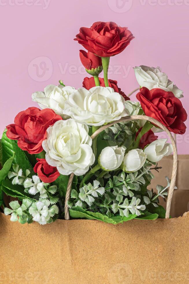 Bouquet of red and white roses in paper bag on pink background, close-up photo
