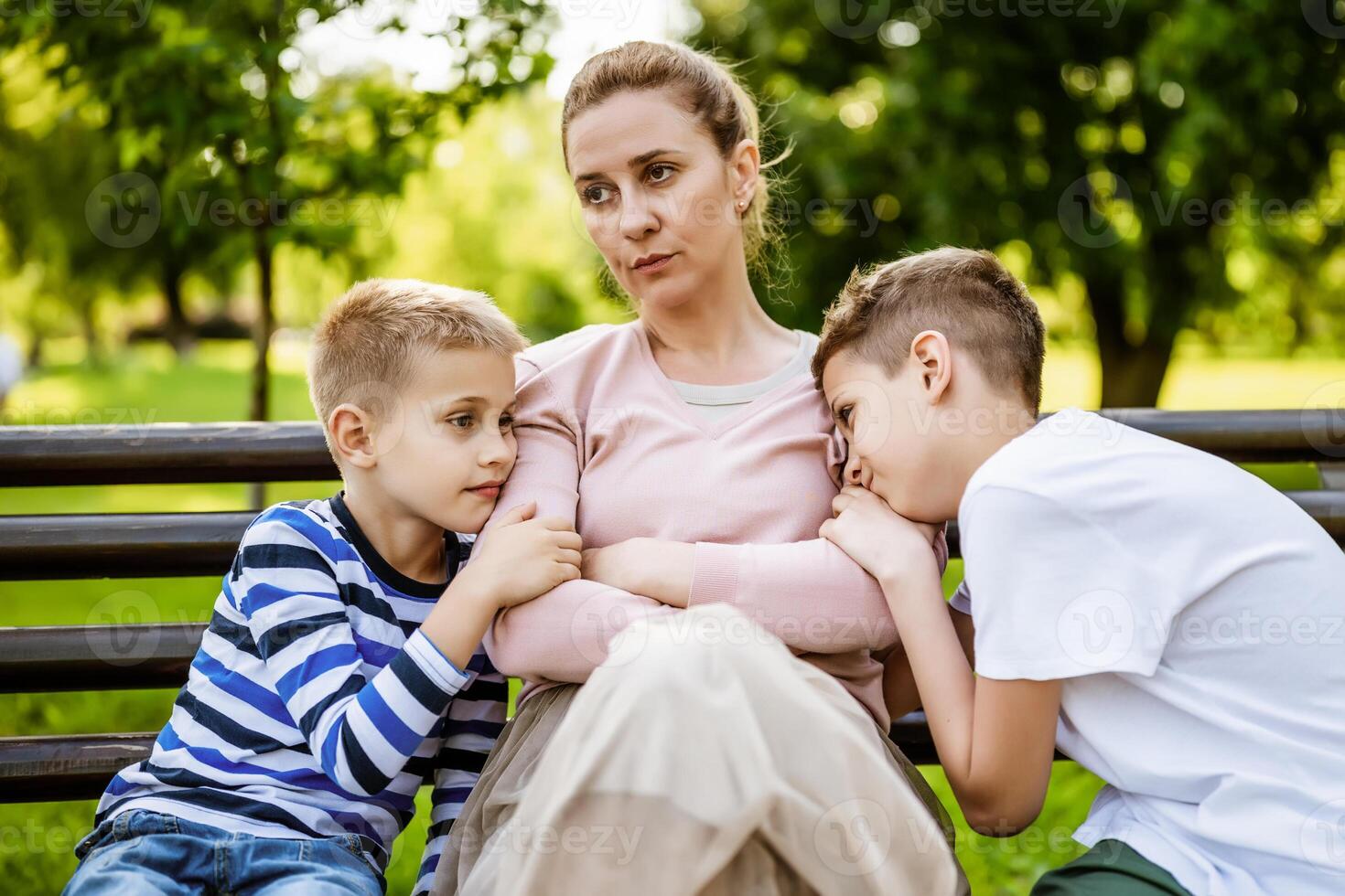 madre es sentado con su hijos en banco en parque. ella es enojado y el Niños tratar a disculparse. foto