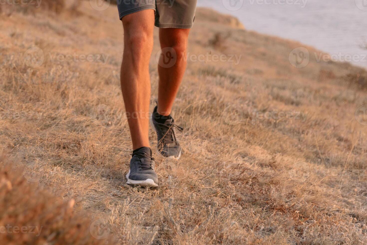 piernas de deportivo hombre caminando al aire libre con calentar puesta de sol. foto