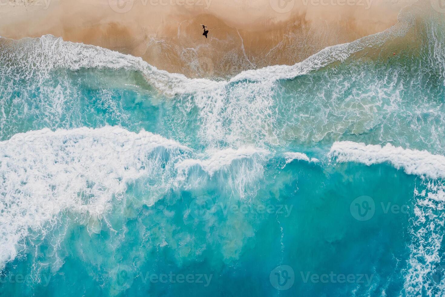 tablista caminar en playa con azul Oceano y ondas. aéreo ver foto