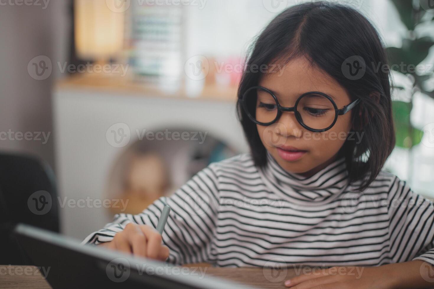 Cute Asian little girl children using a laptop computer, studying through an online e-learning system. photo