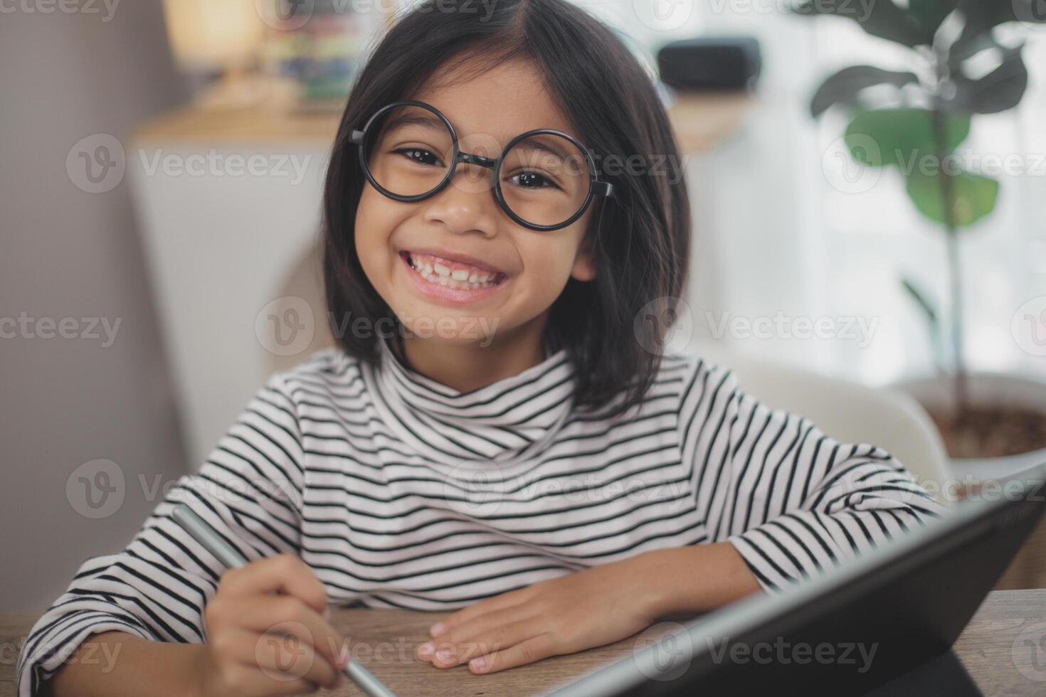 Cute Asian little girl children using a laptop computer, studying through an online e-learning system. photo