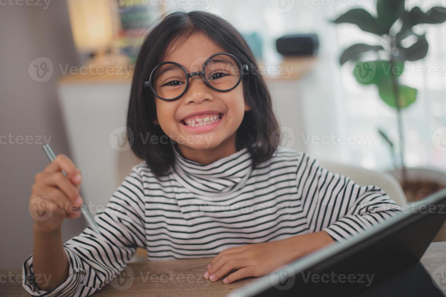 Happy little girl pupil studies online using a laptop at home, smiling small child recommend class or lesson. photo
