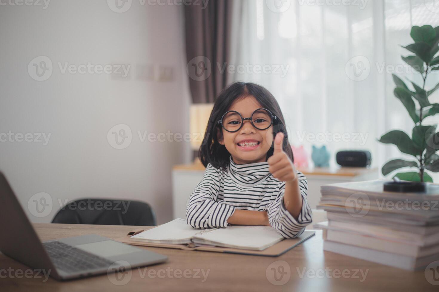 Happy little girl pupil studies online using a laptop at home, smiling small child recommend class or lesson. photo