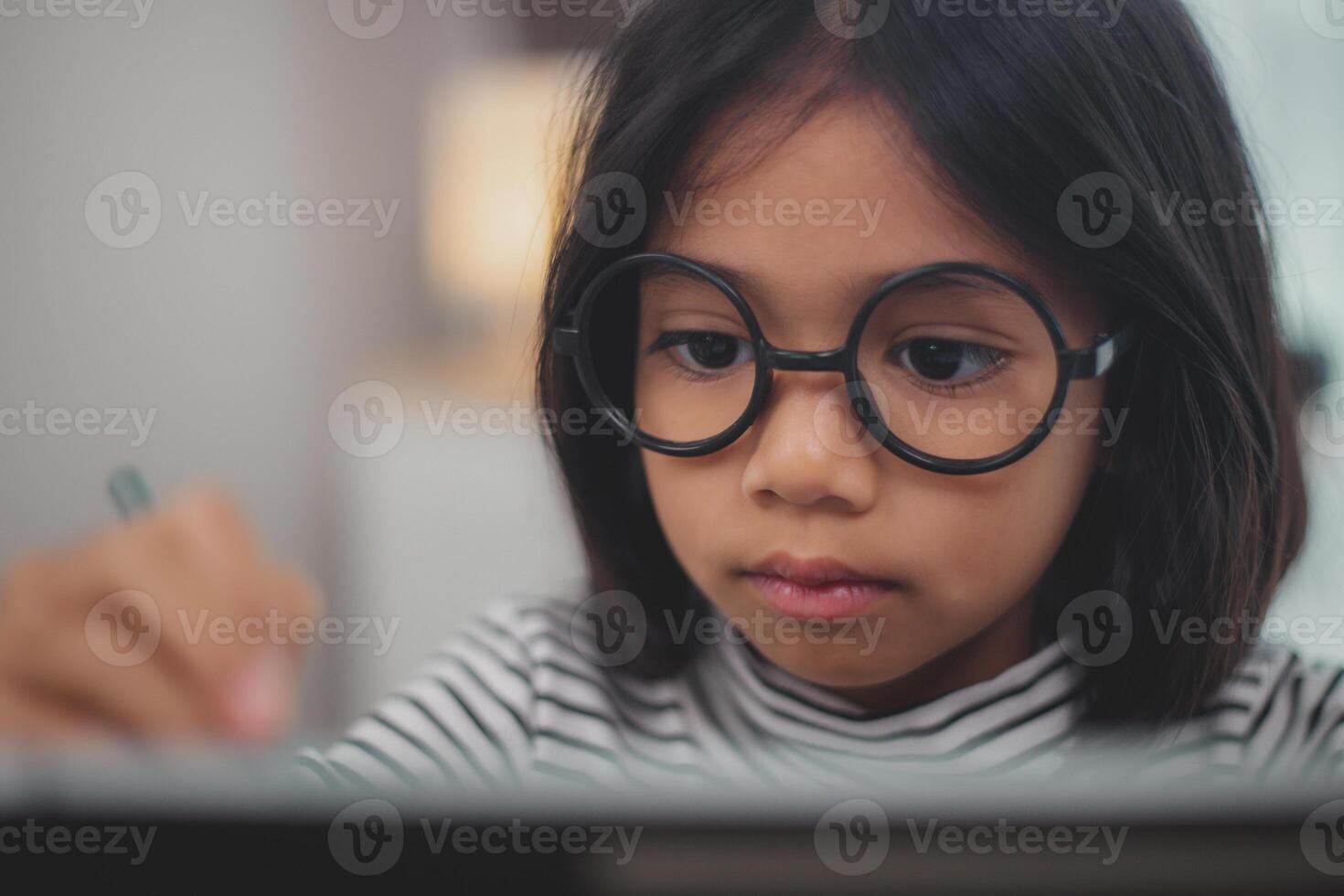 Cute Asian little girl children using a laptop computer, studying through an online e-learning system. photo