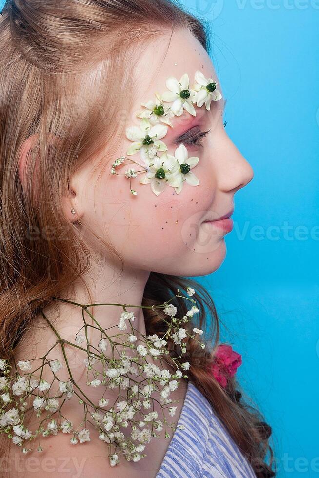 Positive girl. Little girl with daisies in her hands on a blue background. photo