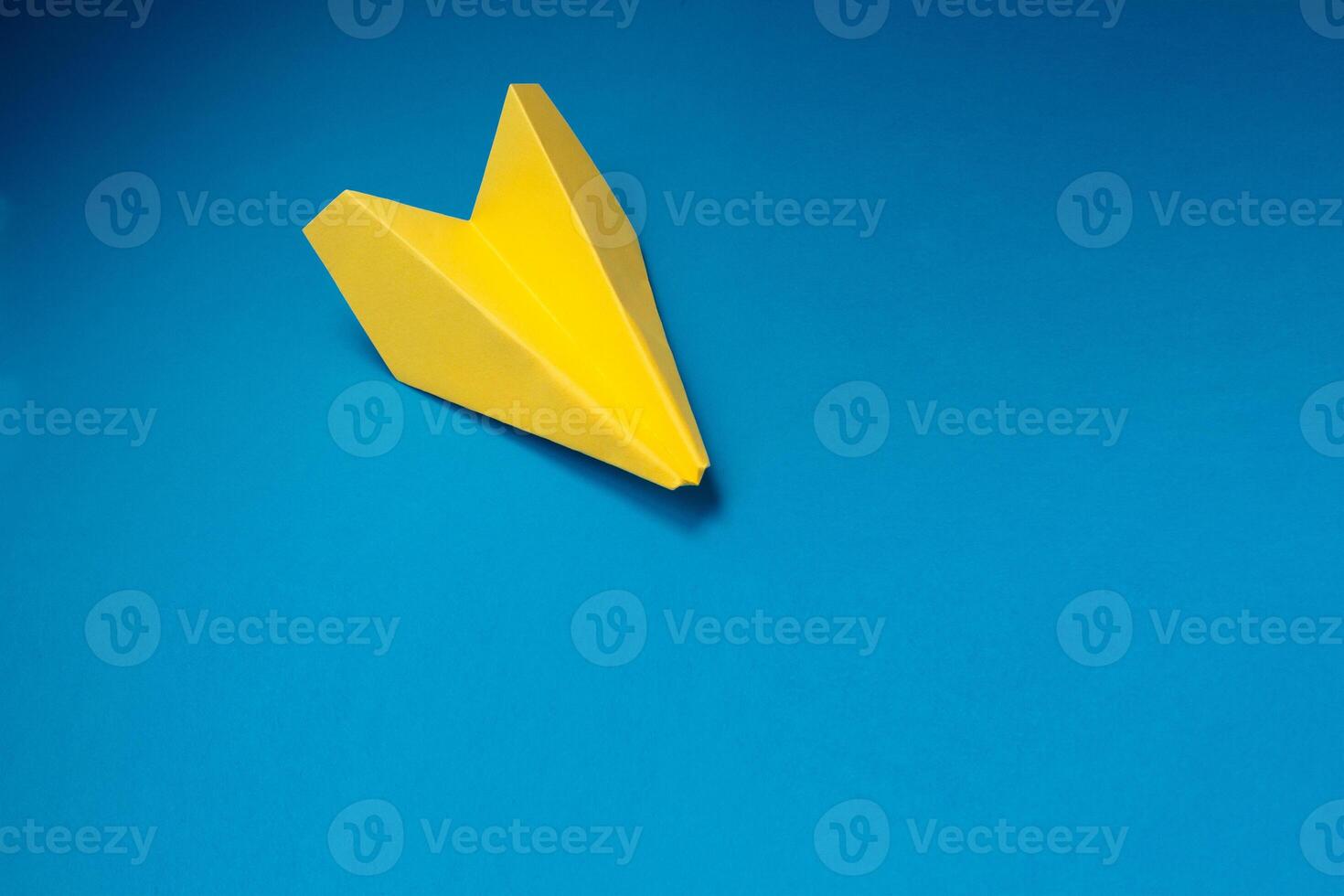 amarillo origami avión en un azul antecedentes. foto