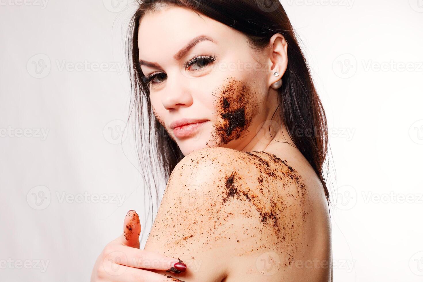 Brunette woman cleans the skin of the body coffee scrub photo