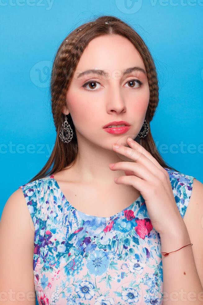 Portrait of happy smiling young beautiful woman in blue casual clothing, over blue background photo