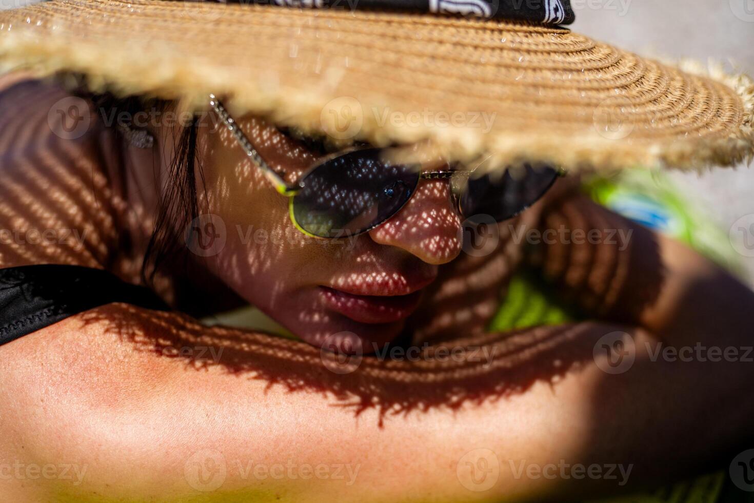 woman in bikini and straw hat lying on tropical beach photo