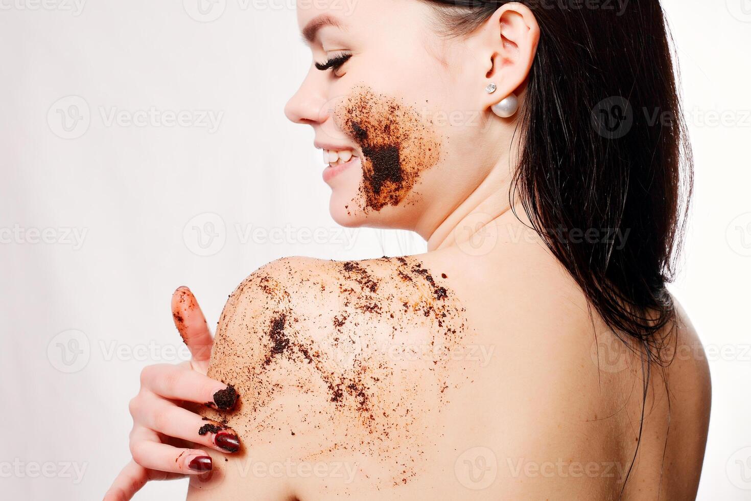 Brunette woman cleans the skin of the body coffee scrub photo