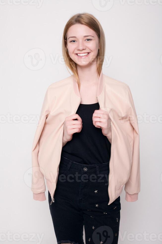 Fashion young woman smiles, confused looking at the camera on a gray background photo