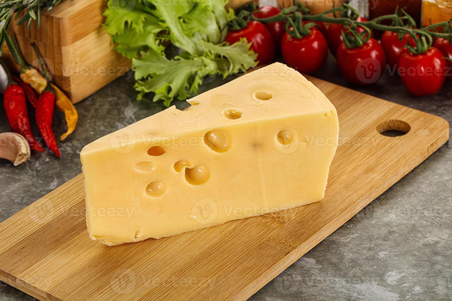 Swiss Maasdam cheese triangle over board photo