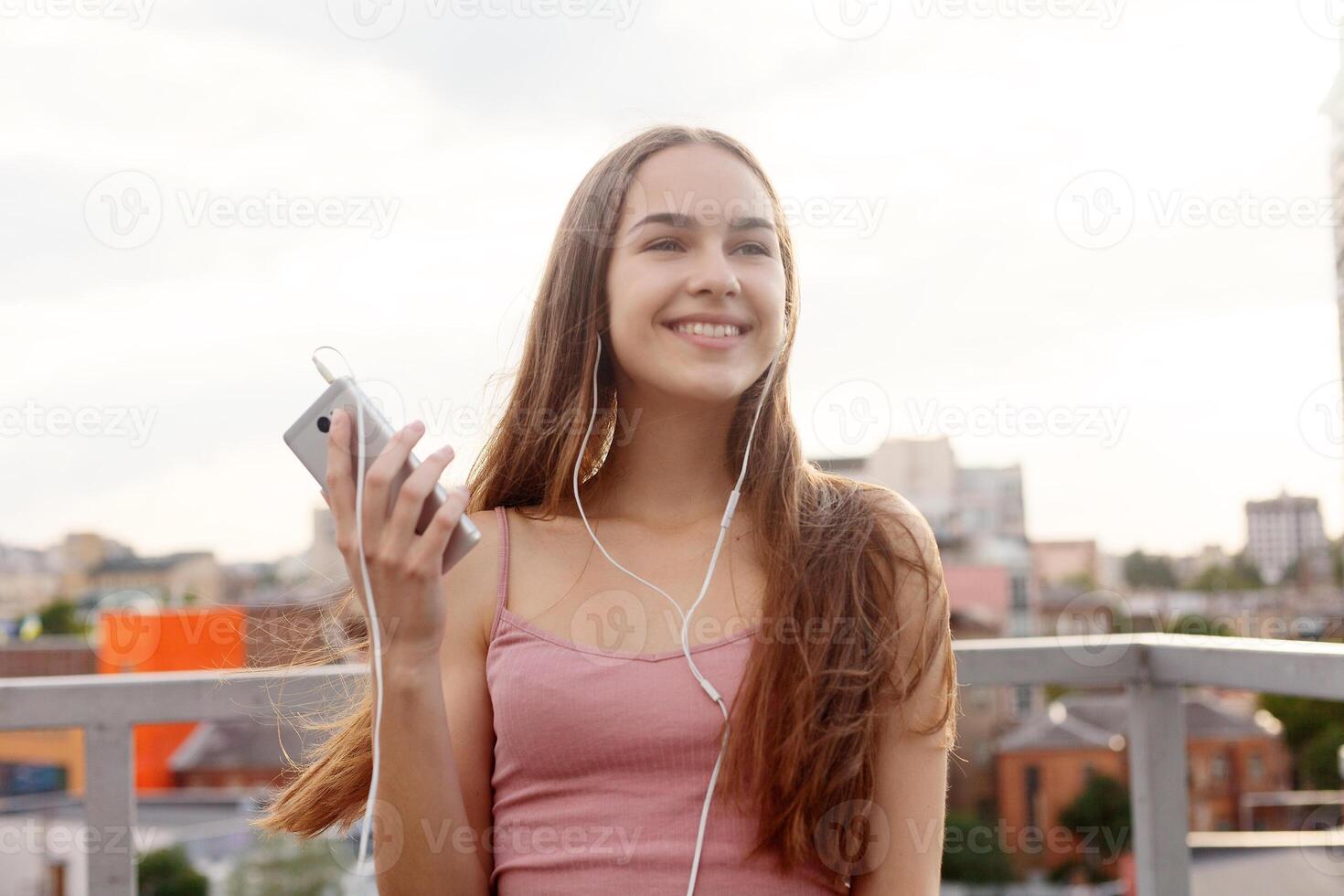 Young woman with headphones dangling on her mobile phone photo