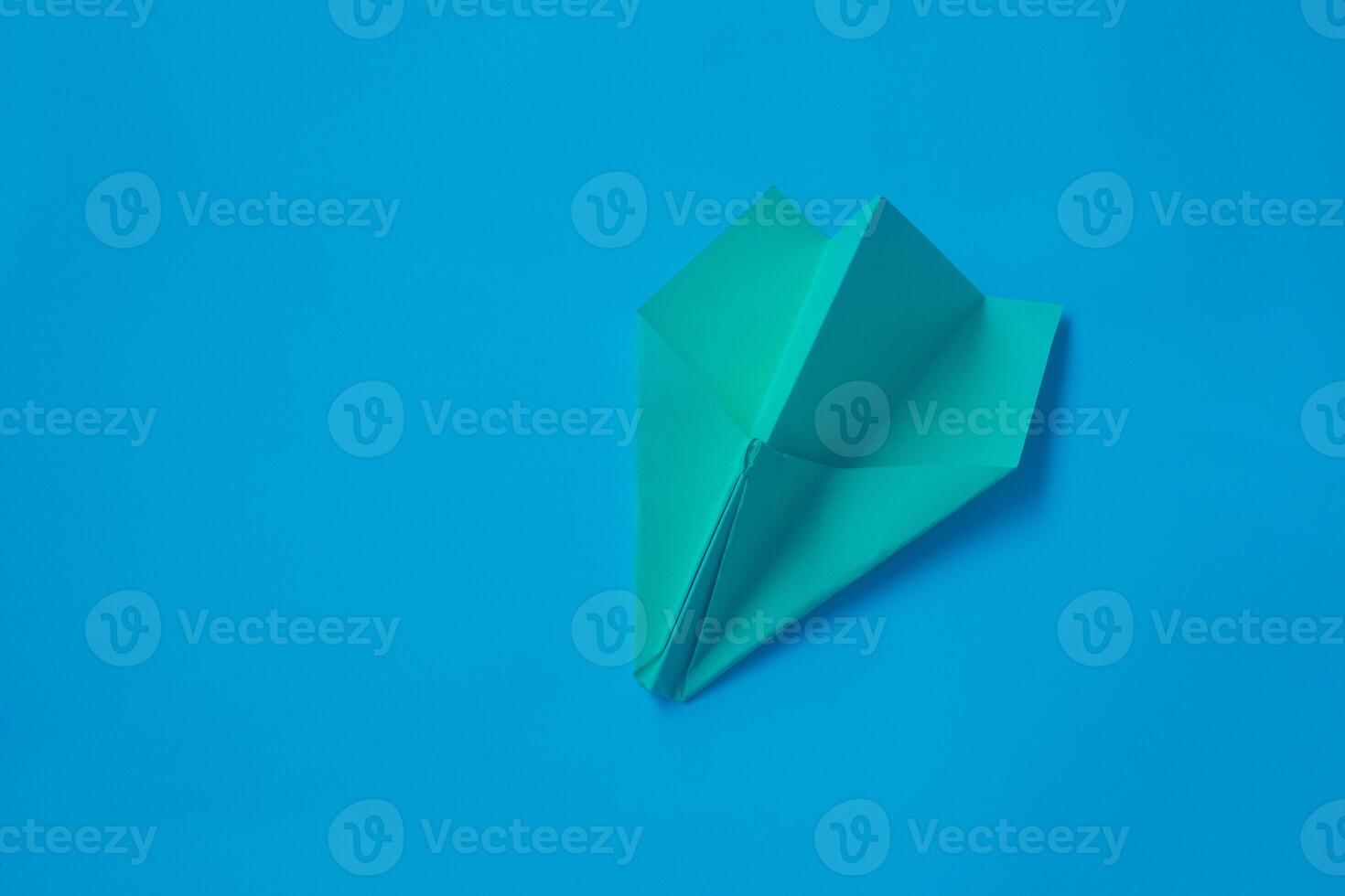Yellow origami plane on a blue background. photo